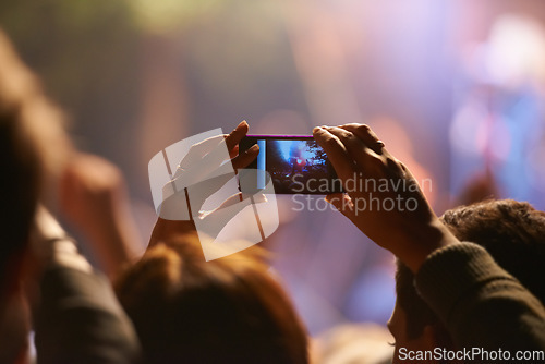 Image of Music, concert and phone camera in the audience to record a performance on stage at a festival or event. Party, video or photograph with a person in the crowd of a stadium at night holding a mobile