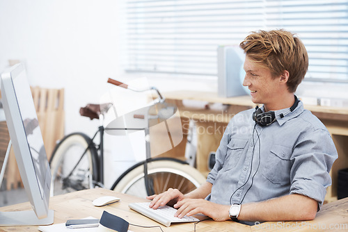 Image of Man, startup office and typing with smile, computer and creativity for post on social media website. Young businessman, entrepreneur and seo expert on web with happiness at small business by computer