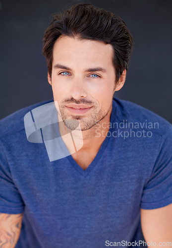 Image of Portrait, fashion and beauty with a sexy man in studio on a gray background for contemporary style. Face, happy and blue eyes with a handsome young male model posing in modern or stylish clothes