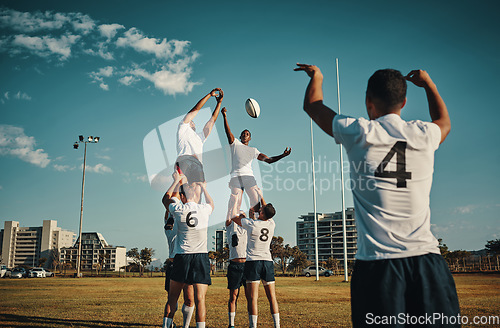 Image of Team, rugby and jump or lift, ball and teamwork or sport, training for game and fitness, exercise or sports performance with blue sky. Group, men and lifting man to catch and professional match