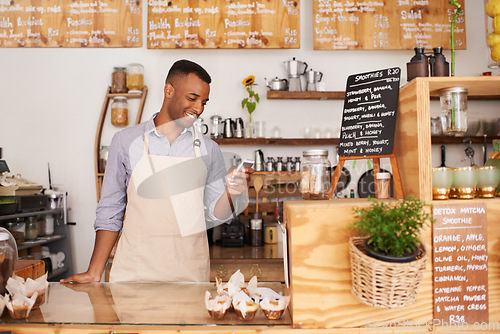 Image of Man, coffee shop and phone of a waiter with happiness from small business. Cafe, mobile and African barista entrepreneur looking on online order app with smile at bakery and restaurant feeling happy