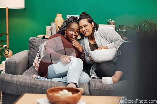 Image of Girl friends, shocking movie and home living room laughing on a couch with a happy smile. Tv, relax and women together in a lounge with a female friend looking at a television in house with popcorn