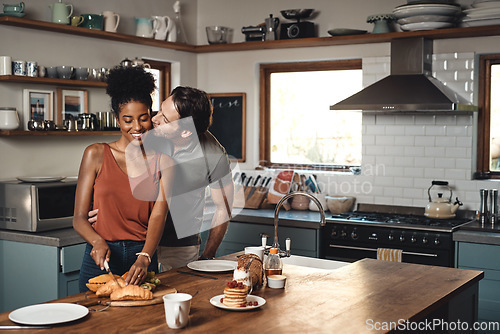 Image of Interracial couple, kiss and cooking breakfast in kitchen for morning, love or care in marriage at home. Happy man kissing woman for food, nutrition or hug in happiness for healthy relationship