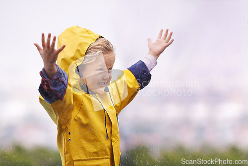 Image of Girl, outdoor and playing in rain with happiness, hands and freedom in backyard, park or garden. Young female child, open palm and excited face with raincoat, winter fashion and playful in raindrops