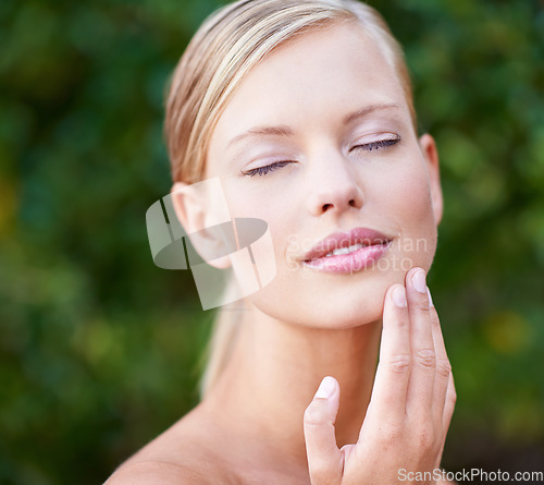 Image of Skincare, beauty and a woman touching face in a garden nature or backyard. Content, wellness and a young lady feeling skin for moisturizing, satisfaction or wellbeing glow from a spa treatment