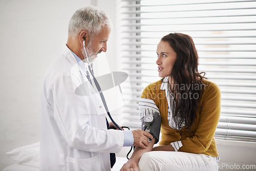 Image of Doctor, blood pressure and a woman patient at hospital for a consultation with health insurance. Man with a stethoscope to check pulse of person for medical exam, wellness and hypertension diagnosis