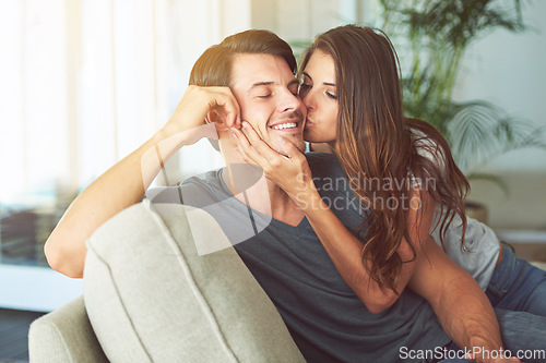 Image of Woman, kiss and man on cheek for couple relax at home in love, intimacy and happy spending time together. Happiness, commitment or trust in relationship with people in living room, affection and care