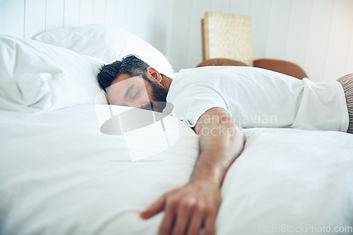 Image of Tired, dream and a man on a bed for sleep, relax and fatigue at home. Rest, napping and a guy sleeping in the bedroom with insomnia, narcolepsy or content while lying down and dreaming in the morning