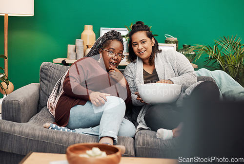 Image of Girl friends, tv and surprise in home living room on a couch with a happy smile. Series, movie and women together in a lounge with a female friend looking at a television in house with popcorn