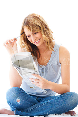 Image of Newspaper, crossword puzzle and a woman sitting crossed legs in studio isolated on a white background. Smile, thinking a problem solving with a happy female person enjoying a mental hobby to relax