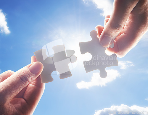 Image of Hands, puzzle and blue sky with business people team building a solution outdoor from below. Collaboration, teamwork and problem solving with colleagues holding jigsaw pieces for strategy or planning