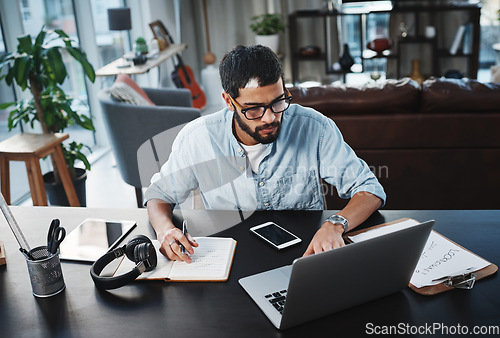 Image of Laptop, remote work and man with a notebook for planning a creative freelance project at his home. Technology, reading and male freelancer doing research on computer while working in his living room.