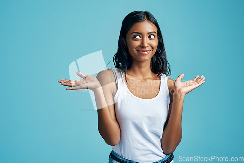 Image of Options, thinking and woman with a gesture in a studio with a confused, unsure or uncertain face. Decision, doubt and Indian female model with choice or shrug hand sign by blue background with mockup