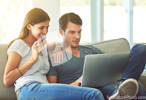 Image of Couple, laptop and credit card for online shopping on home sofa with secure fintech payment on website. A man and woman together on a couch while happy about e-commerce and internet connection