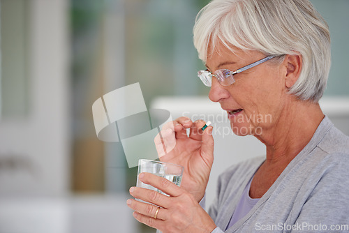 Image of Medication, health and woman drinking a pill for recovery, medical problem or wellness at a retirement home. Medicine, sick and senior female person taking a prescription tablet with a glass of water