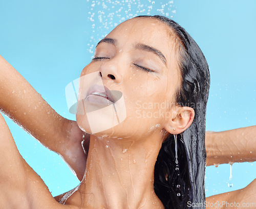 Image of Shower, cleaning and woman washing hair in studio for beauty, wellness and hygiene on blue background. Haircare, skincare and female model relax in water splash, showering and cleansing isolated