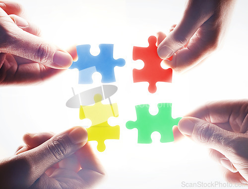 Image of Hands, puzzle and teamwork in group, problem solving or together for support, glow or color by white background. Team building, jigsaw or strategy for innovation, synergy or solution in collaboration