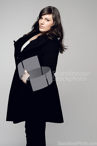 Image of Woman, fashion and portrait of plus size model posing in winter clothing against grey studio background. Isolated female person standing with stylish black coat or warm fashionable clothes for beauty