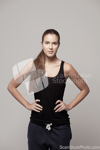 Image of Woman akimbo, portrait and fitness confidence with arms on hip for body, health or wellness on a gray studio background. Happy and confident female person or model posing in cardio exercise clothing