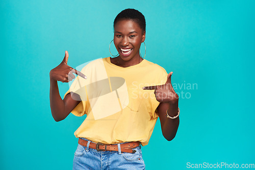 Image of Portrait, crazy and pointing with a black woman in studio on a blue background looking carefree or silly. Smile, fashion and fun with a happy young female hipster feeling confident or playful