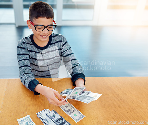 Image of Savings, young child counting money and sitting at desk at his home. Finance or investing, financial management or wealth planning and happy male kid with cash for future investment in house