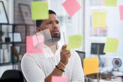 Image of Serious man, thinking and brainstorming notes of business, solution, strategy and mindmap at glass window. Focused face of male worker planning schedule, problem solving and ideas for project goals