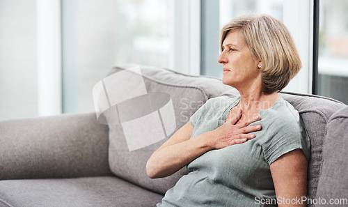 Image of Heart attack, chest and senior woman with pain in her home living room or couch with an emergency or crisis on a sofa. Asthma, medical and sick elderly person with discomfort due to illness