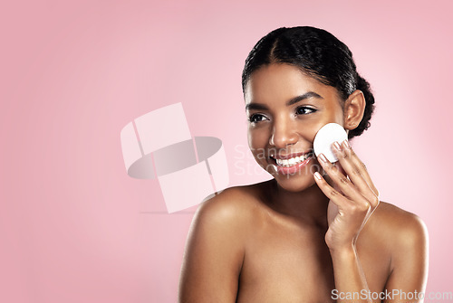 Image of Skincare, mockup and happy woman with cotton pad on face, smile and makeup removal with skin product in studio. Dermatology, facial cleansing cosmetics and African model isolated on pink background.