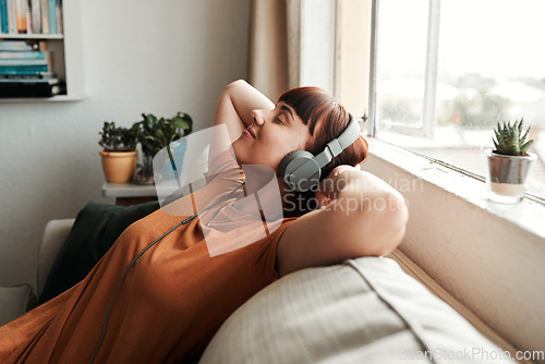 Image of Relax, headphones and woman listening to music, podcast or radio while resting on a sofa. Calm, chill and female person streaming album, playlist or song while sleeping in the living room of her home