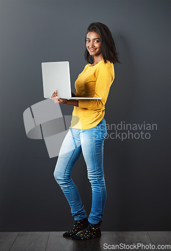 Image of Portrait, happy indian woman standing with laptop and in wall background. Social media or networking, technology or communication and smiling African female worker with mockup in studio backdrop.