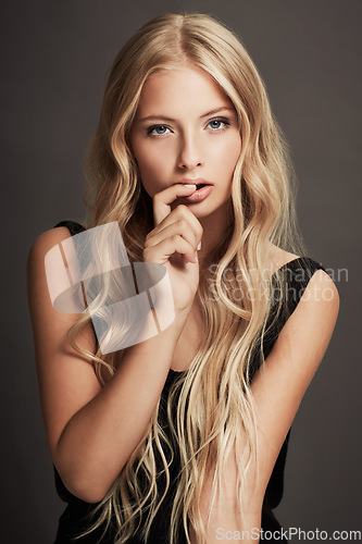 Image of Beauty, face and portrait of a seductive woman with makeup, cosmetics and long hair in studio. Sexy female aesthetic model with skin glow, luxury skincare and finger in mouth on a grey background