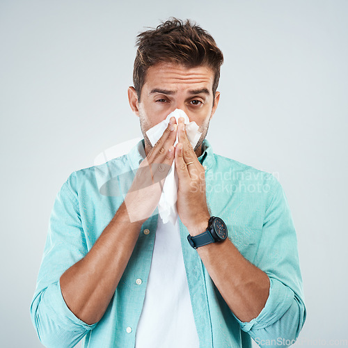 Image of Sick, tissue and portrait of man blowing nose in studio with flu, illness and virus on white background. Health, wellness and face of male person with hayfever, cold symptoms and sneeze for allergy