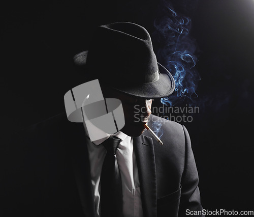 Image of Man, gangster and cigarette in studio by black background with smoke, silhouette and dangerous in shadow. Mafia, secret agent or male in night for smoking with vintage aesthetic by dark backdrop