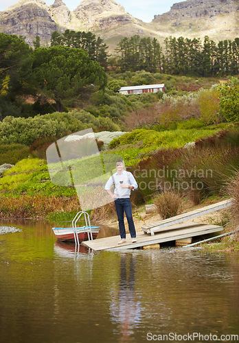 Image of Portrait, river and a man drinking red wine on a pier outdoor in nature on his farm for agriculture. Water, drink and alcohol with a happy farmer enjoying a beverage while farming for sustainability