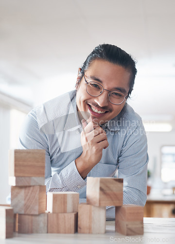 Image of Portrait of businessman with smile, growth and blocks, thinking challenge game and design balance. Engineering, architecture and happiness, asian designer with building block problem solving games.