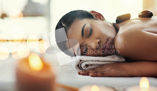 Image of Woman, relax and sleeping on bed at spa for rock massage, skincare or beauty body treatment at resort. Calm female asleep with eyes closed and hot rocks on back in healthy physical therapy at salon