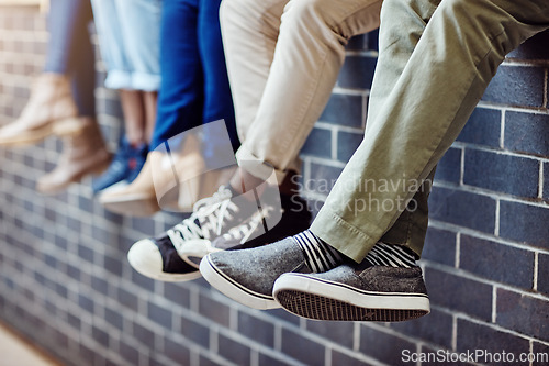 Image of Brick wall, student feet and friends outdoor on university campus together with sneakers. Relax, urban youth and foot at college with people legs ready for education, study and shoes while sitting