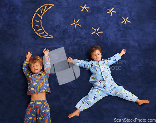Image of Boy kids in pajamas, sleeping on carpet with moon and stars design, top view and young children dreaming. Peace, calm and tired brothers or friends sleep on galaxy art on mat at family home