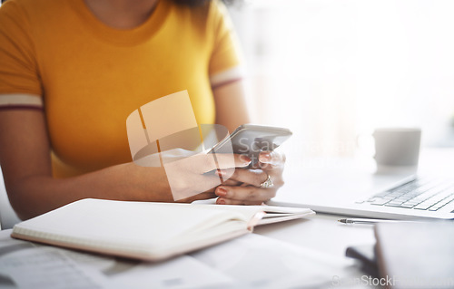 Image of Hands, woman with a smartphone and laptop by her desk in office. Social media or communication, connectivity or networking and female worker on cellphone reading or writing an email at workplace