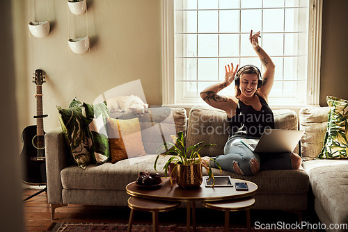 Image of Music, headphones and woman on sofa and laptop dancing, happy energy and mental health in boho apartment. Young person listening to audio technology, electronics and computer in living room or home