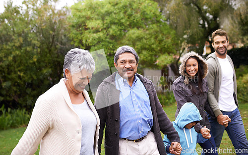 Image of Big family, smile and holding hands in park with kid, parents and grandparents with love, care or happiness. Group, senior people and child with bonding, walk and freedom in garden, nature or holiday