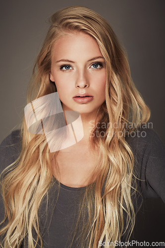 Image of Face, beauty and portrait of a woman in studio with makeup, cosmetics and long hair. Headshot of a female aesthetic model with a natural glow, luxury skincare and seductive pose on a grey background