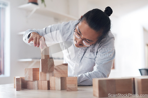 Image of Man in office with wood block game, thinking challenge and design innovation for balance and construction. Engineering, architecture and asian designer with building blocks for problem solving games.