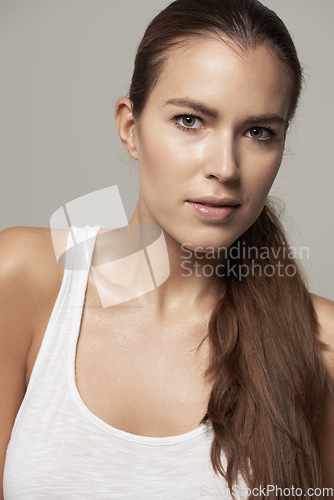 Image of Serious woman, portrait and natural beauty in skincare or facial cosmetics against grey studio background. Isolated female person, face or model in cosmetic haircare in active sportswear on backdrop
