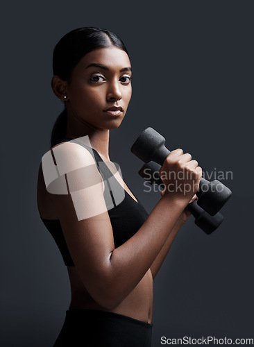 Image of Serious, portrait and woman with dumbbells for workout in studio isolated on a black background. Strong, bodybuilder and Indian female athlete weightlifting for muscle, training and fitness exercise.