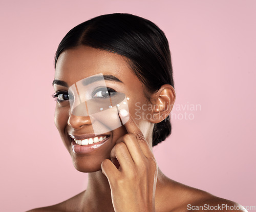 Image of Smile, skincare and face of woman with cream in studio isolated on a pink background. Dermatology, creme cosmetics and portrait of happy Indian female model apply moisturizer lotion for healthy skin.