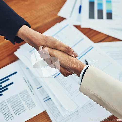 Image of Business people, handshake and partnership in meeting above for b2b, deal or document agreement at the office. Top view of employees shaking hands for planning, strategy or teamwork at the workplace