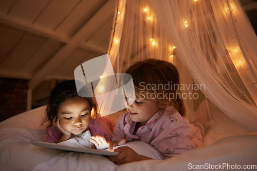 Image of Bed, night and girls with a tablet, movie and playing games with happiness, online reading and relax. Female children, happy kids and young people in a bedroom, evening and technology for fun and app