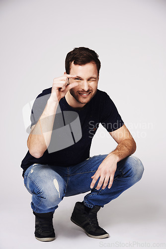 Image of Size, small and hand gesture with portrait of man in studio for sign, opinion and measurement. Happy, smile and idea with male person isolated on white background for scale, review and happiness