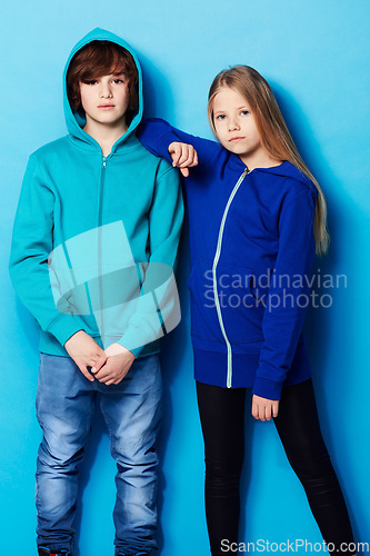 Image of Fashion, portrait and young girl and boy in a studio with a casual, cool and stylish outfit. Youth, friendship and portrait of teenager models posing together with trendy style by a blue background.